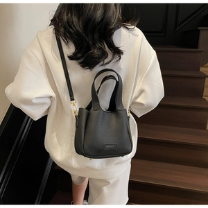 Detailed back view of a black lychee leather bucket bag with gold hardware and strap