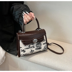 Detail of printed canvas handbag with brown leather flap and round metal rotary buckle