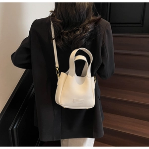 Detail of cream leather bucket bag with pebble texture and adjustable crossbody strap