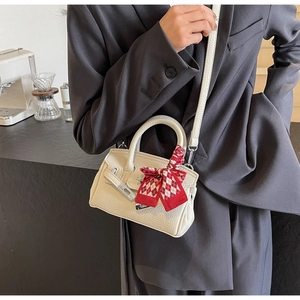 Detailansicht der cremefarbenen Mini-Handtasche mit Seidenschal und Metallschloss-Verzierung