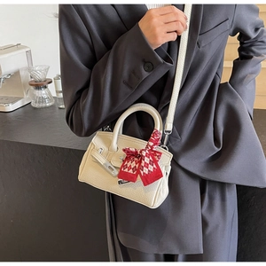 Detail der cremeweißen Mini-Tasche aus Leder mit rot-kariertem Seidenschal am Griff