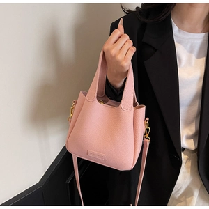 Detail of pink lychee grain leather bucket bag with gold hardware and shoulder strap