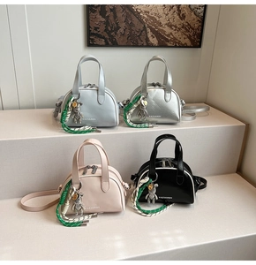 Detail view of four compact crossbody bags in silver, pink, and black with bear charms