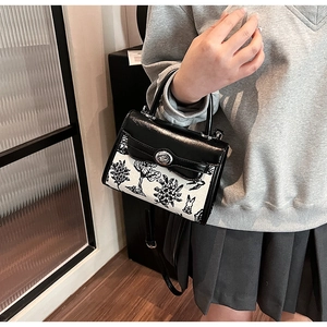 Detail of crossbody bag featuring black floral rabbit print and silver metal twist lock