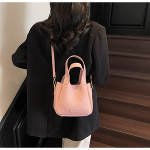 Detailed back view of pink lychee leather bucket bag worn by model on a shoulder strap