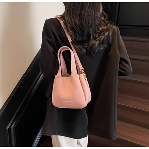 Detailed close-up of pink lychee grain leather bucket bag with gold hardware and strap