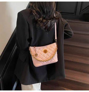 Detailed view of pink quilted patent leather bucket bag with gold chain on model