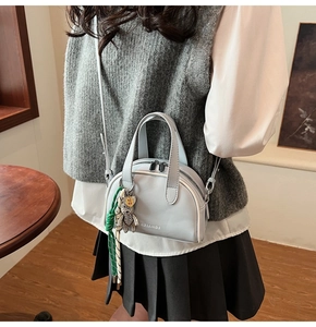 Detail of light blue square bag featuring bear charm and dual zipper on vegan leather