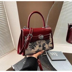 Detail of red leather crossbody bag featuring rabbit and tree embroidery patterns