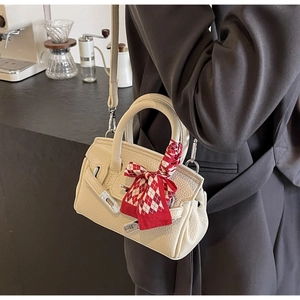 Detail der cremefarbenen Handtasche aus Leder mit Seidenschal und metallischem Verschluss