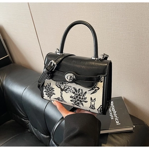 Detail of Toile de Jouy print and black leather accents on a mini Kelly handbag