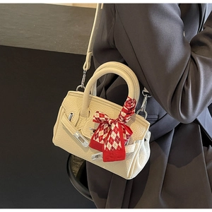 Detail der cremefarbenen Mini-Handtasche mit Lederstruktur und rotem Seidenschal