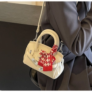 Nahaufnahme der cremefarbenen Ledertasche mit seidenschalumwickeltem Griff und Schnalle