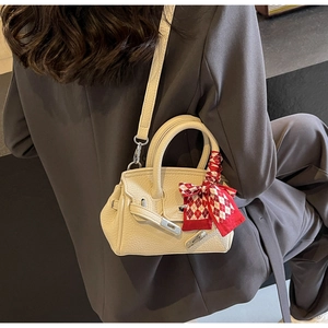 Detail der cremeweißen Lederhandtasche mit rot-kariertem Seidentuch und Silberschnalle