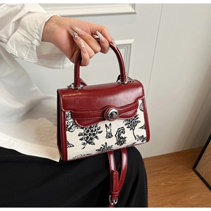Close-up of red leather crossbody bag featuring a bunny illustration and silver twist lock