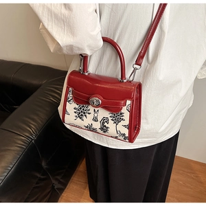 Detail of red leather and printed canvas kelly bag with metal twist lock clasp