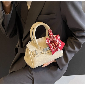 Detailansicht der weißen Lederhandtasche mit rot-weißem Karoschal am Griff für Damen