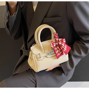 Detailansicht der beigen Lederhandtasche mit Seidenschal am Griff und Silberverschluss