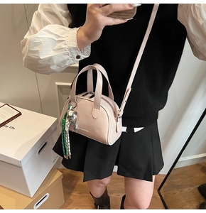 Detail of pink faux leather crossbody bag with silver bear charm and woven cord on model