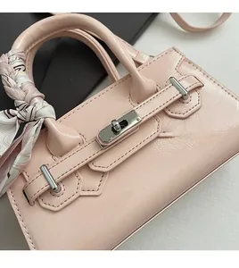 Detail einer hellrosa Lackleder-Handtasche mit Silberschloss und dekorativem Seidenschal