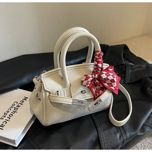 Details einer weißen Lederhandtasche mit silbernem Schloss und kariertem Seidenschal-Griff