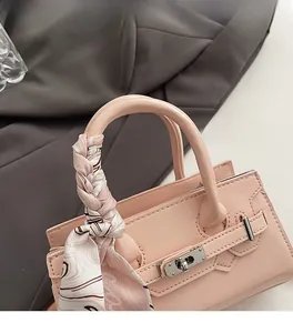 Detail der rosa Lackleder-Handtasche mit Seidentuch am Griff und Metallschloss