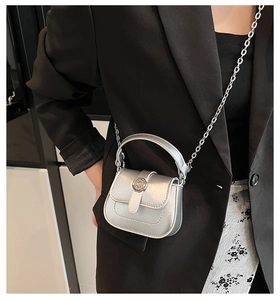 Detail of a mini silver metallic chain bag showing a textured flap and circular buckle