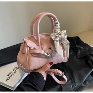 Nahaufnahme der rosa Lederhandtasche mit Silberverschluss und dekorativem Seidenschal