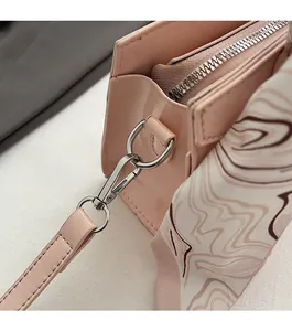 Detail von Silberbeschlägen und dekorativem Seidenschal an rosa Lacklederhandtasche