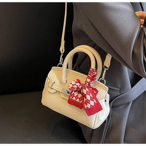 Detail der cremefarbenen Lederhandtasche mit rot-weiß kariertem Seidenschal am Griff