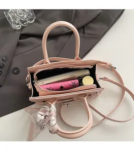 Draufsicht auf offene rosa Handtasche mit Innenraum und gebundenem Seidentuch am Griff