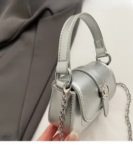 Detail of silver textured mini square bag with metal chain strap and circular metal buckle