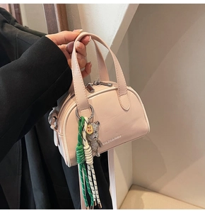 Pink leather handbag with zipper, diamond bear charm, and woven rope detail
