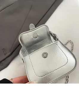Detail shot of the magnetic snap closure and leather texture on a silver mini bag