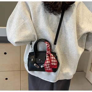 Detail der schwarzen Mini-Tasche aus Kieselleder mit silbernem Schloss und Seidenschal