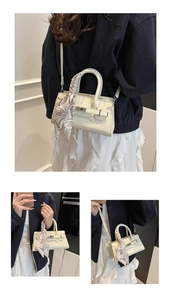 Detailansicht der cremefarbenen Trapez-Handtasche mit dekorativem Seidenschal-Griff