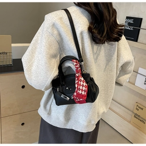 Schwarze Lederhandtasche mit rotem Seidentuch-Detail in einer Lifestyle-Aufnahme