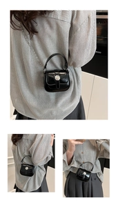 Detail of glossy black patent leather mini square bag with silver metal buckle and chain