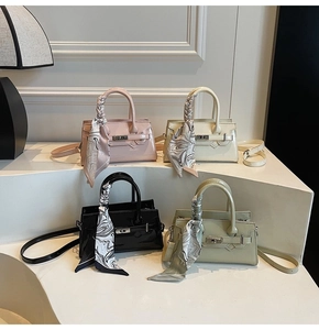Vier bunte quadratische Handtaschen mit seidenem Schal am Griff und edlem Drehverschluss im Detail