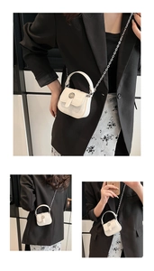 Detailed macro view of white patent leather mini bag with decorative metal flower clasp