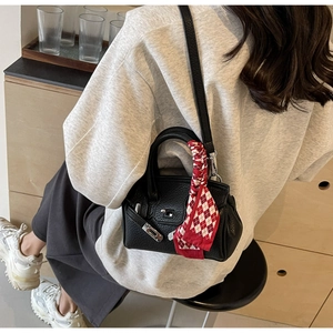 Detail der schwarzen Mini-Handtasche aus Leder mit Seidenschal und silbernem Verschluss