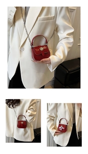 Detail of a mini red patent leather crossbody bag with silver chain and metal buckle