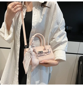 Detail der rosa Mini-Handtasche mit seidenem Schal am Griff und silbernem Drehverschluss