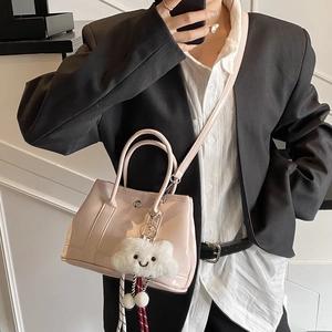 Glossy pink bucket bag with cloud plush pendant shown as hand-held and crossbody style