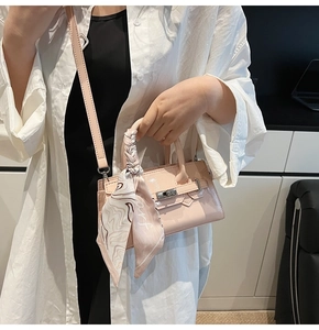 Detail einer hellrosa Mini-Handtasche mit dekorativem Seidentuch und silbernem Schloss