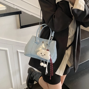 Chic light blue patent leather bucket bag with cloud charm shown in a fashion setting
