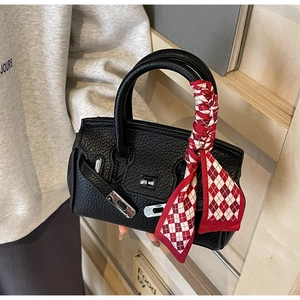 Detailansicht schwarzer Lederhandtasche mit rot-weißem kariertem Seidenschal am Griff