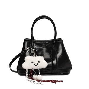 Glossy black bucket bag with a plush cloud charm and detachable shoulder strap