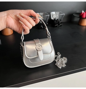 Detail of silver mini square bag featuring metallic finish and C-shaped metal buckle clasp