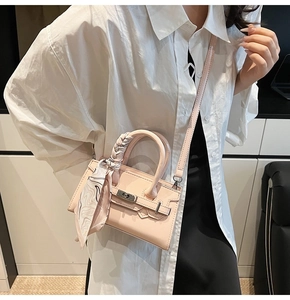 Detail einer hellrosa Mini-Handtasche mit Seidenschal-Griff und elegantem Drehverschluss